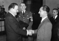 Wilhelm Kreis (1.v.l.) erhält den Adlerschild des Deutschen Reiches, überreicht von Joseph Goebbels (3.v.l.). Quellennachweis: Bundesarchiv, Bild 146-1971-016-21 / Unbekannt / CC-BY-SA 3.0 (wikimedia).