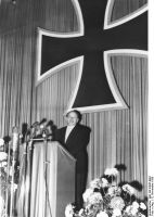 Bundesminister der Verteidigung Theodor Blank am Rednerpult bei Ansprache zur Überreichung der Ernennungsurkunden für die ersten 101 Freiwilligen der Bundeswehr (12.11.1955)