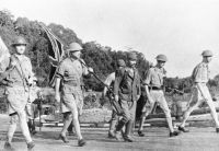 Lieutenant-General Arthur Percival (2. v. links mit Union Jack) und seine Offiziere schreiten zur Unterzeichnung der Kapitulation Singapurs am 15. Februar 1942.Quelle: Imperial War Museum (public domain).